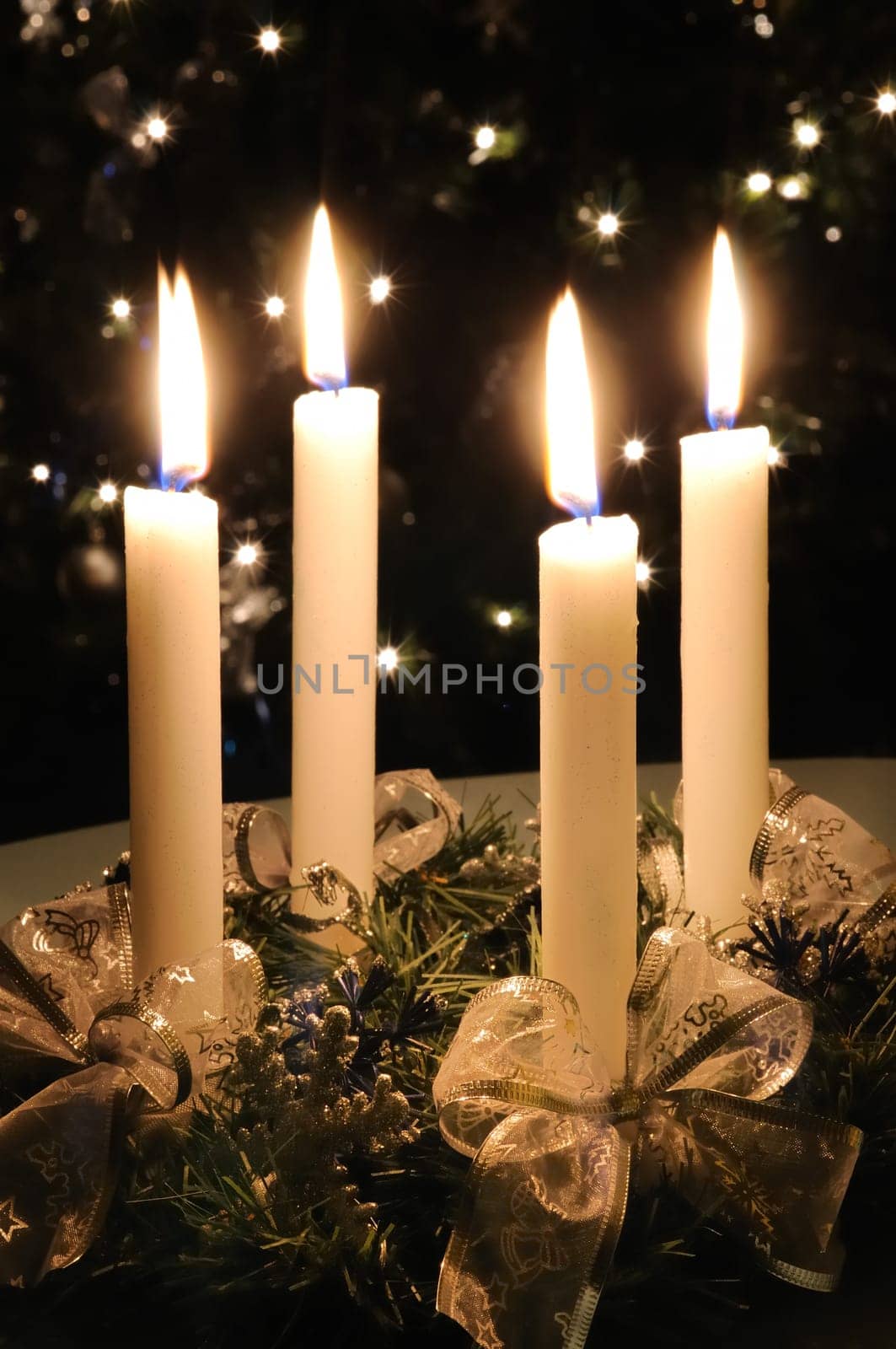 Christmas advent wreath with burning candles. Lights on x-mas tree in background