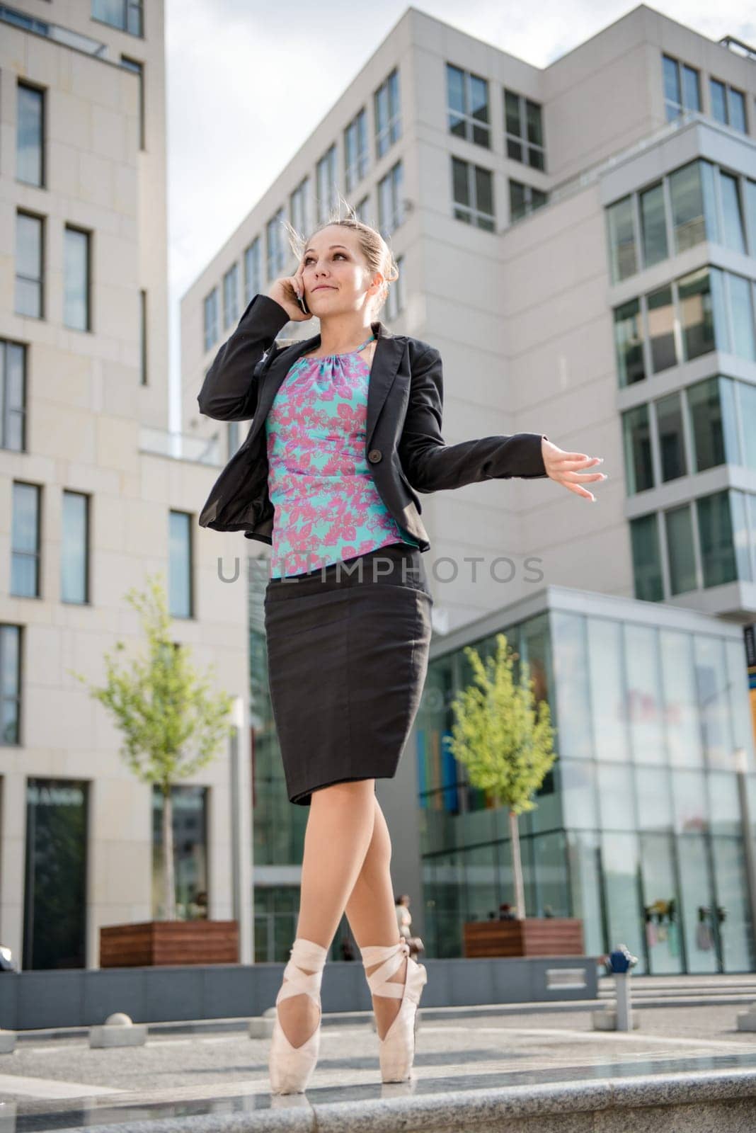 Ballet dancer dressed in business clothes calling with mobile phone