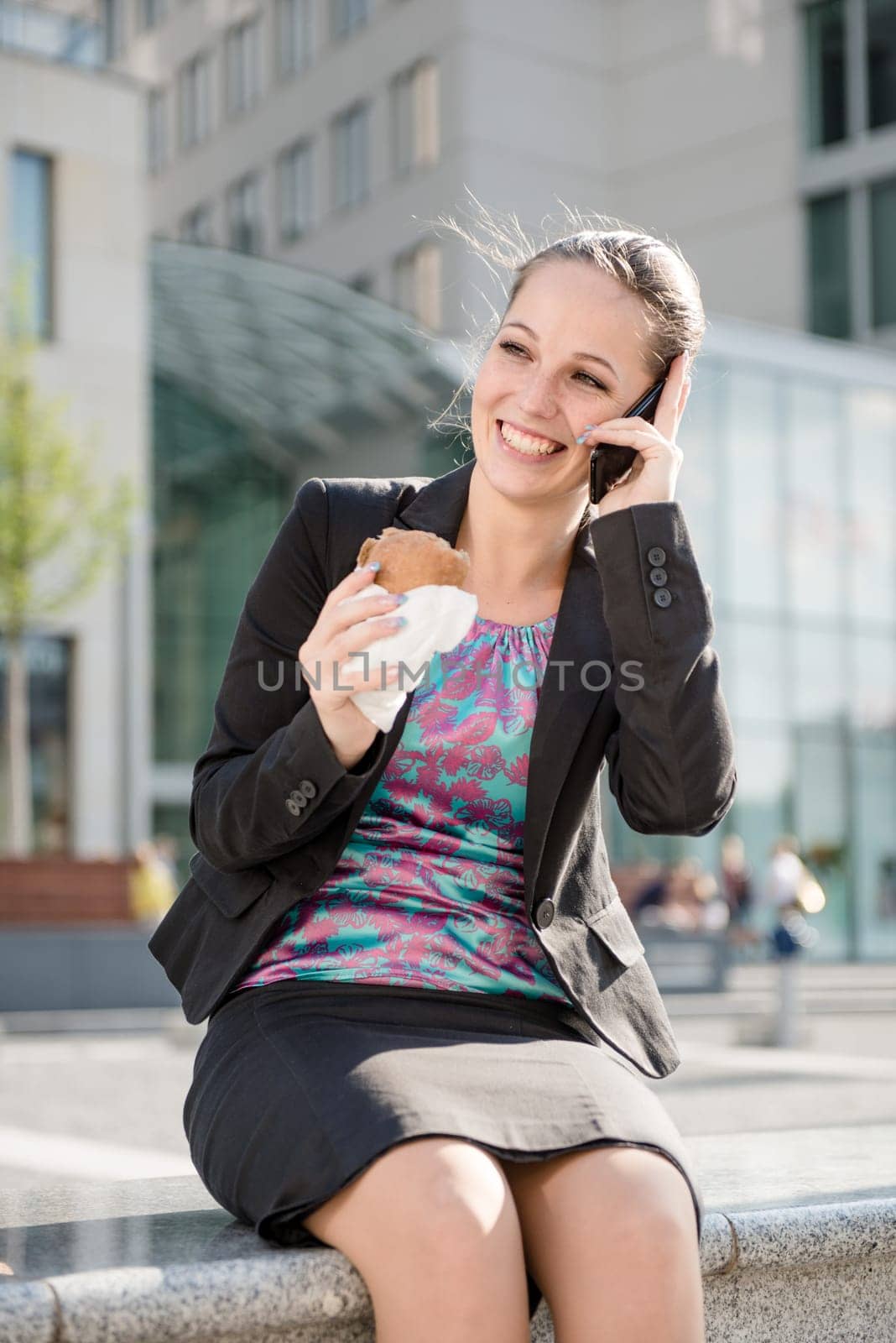 Young eating business woman calling with mobile phone - urban environment