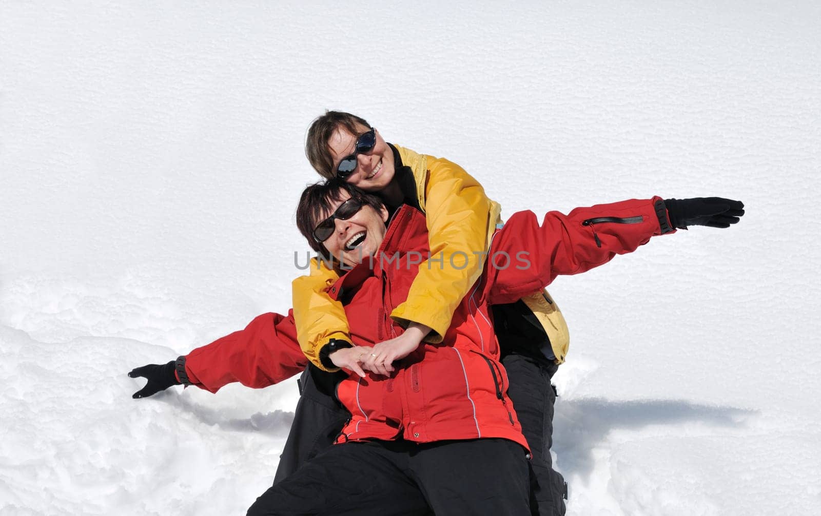 Mature senior woman has happy time with her daughter on fresh white snow in winter season