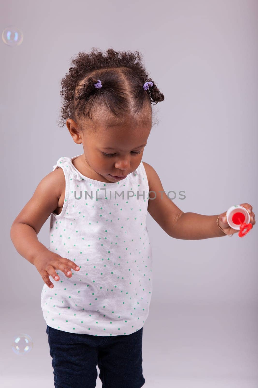 Cute little African American girl playing with soap bubbles