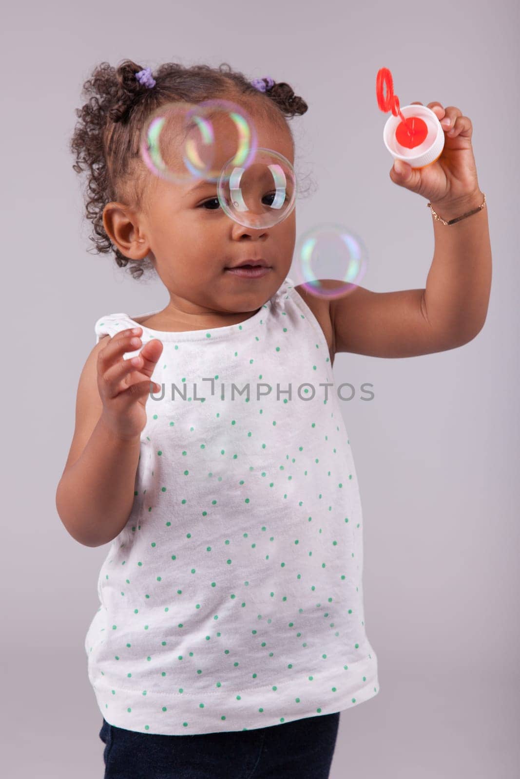 Cute little African American girl playing with soap bubbles
