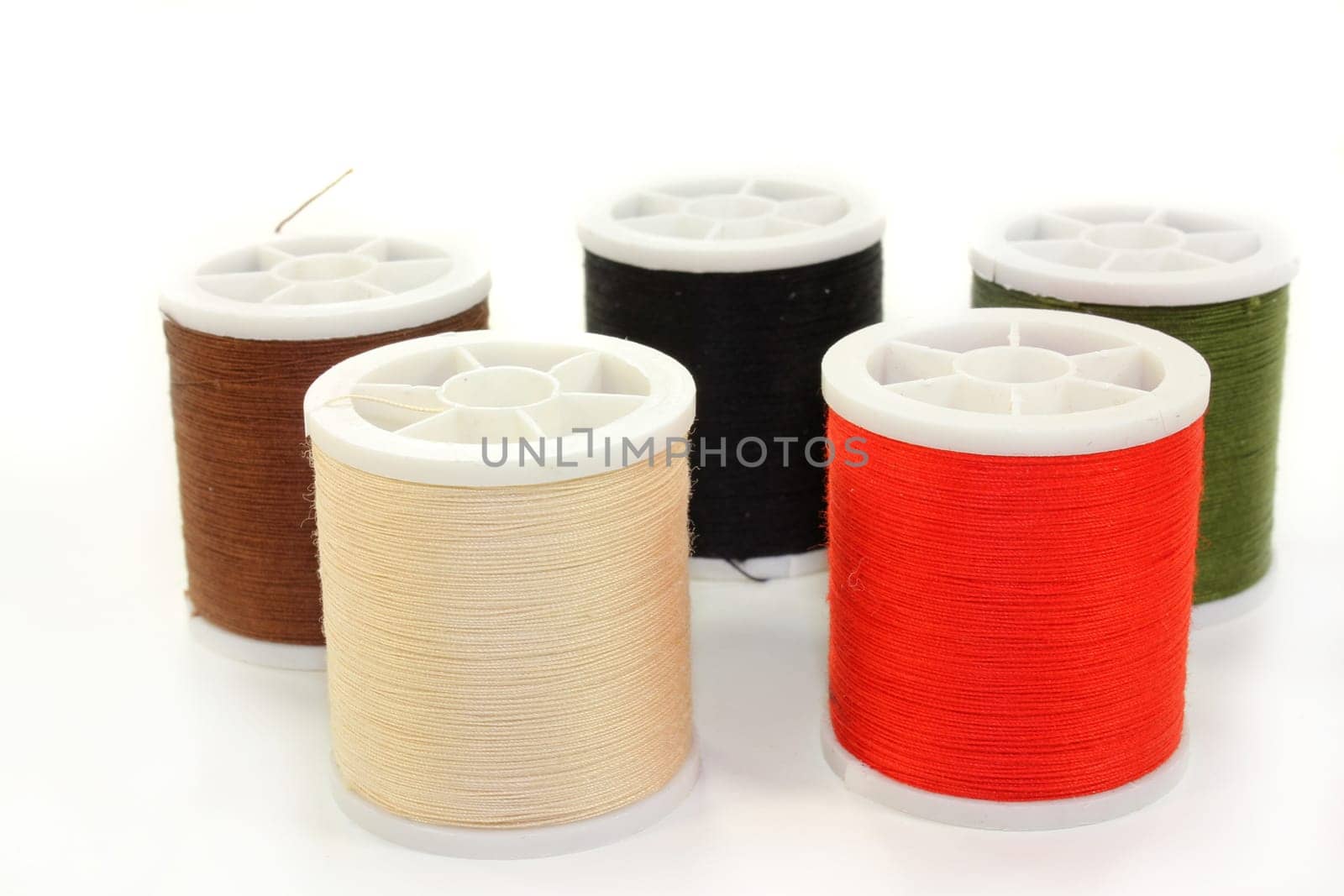 Different colored sewing thread against white background