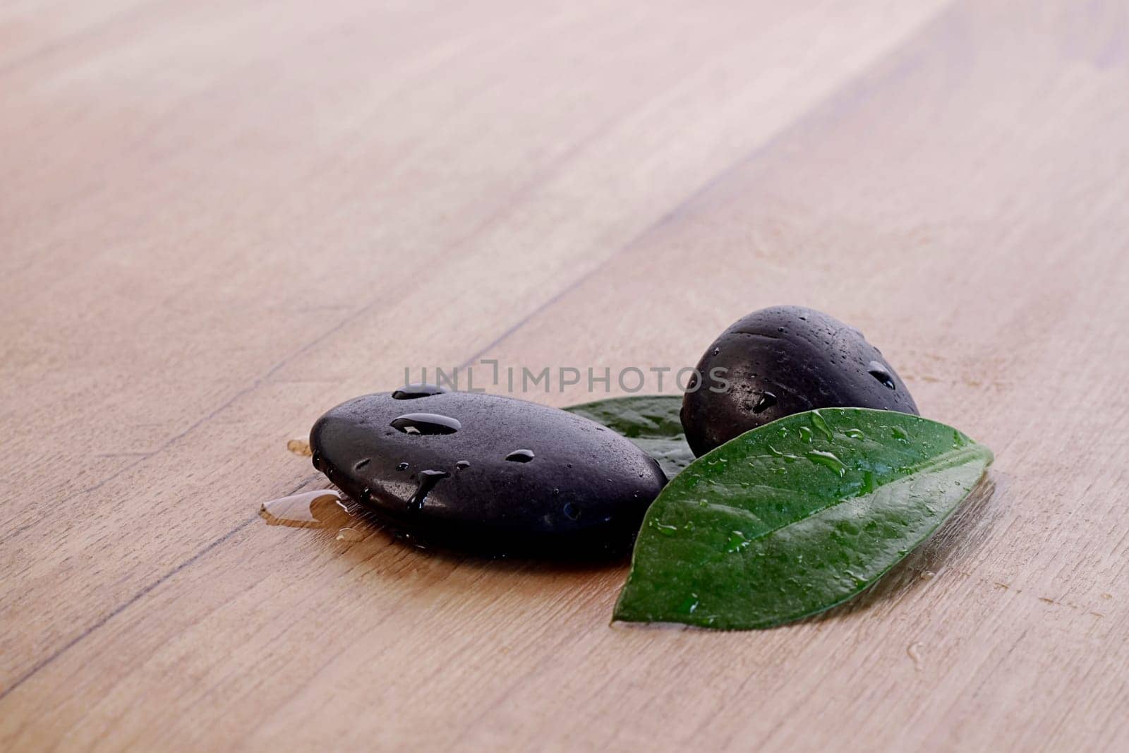Hot Stones with green leafs on a wooden background