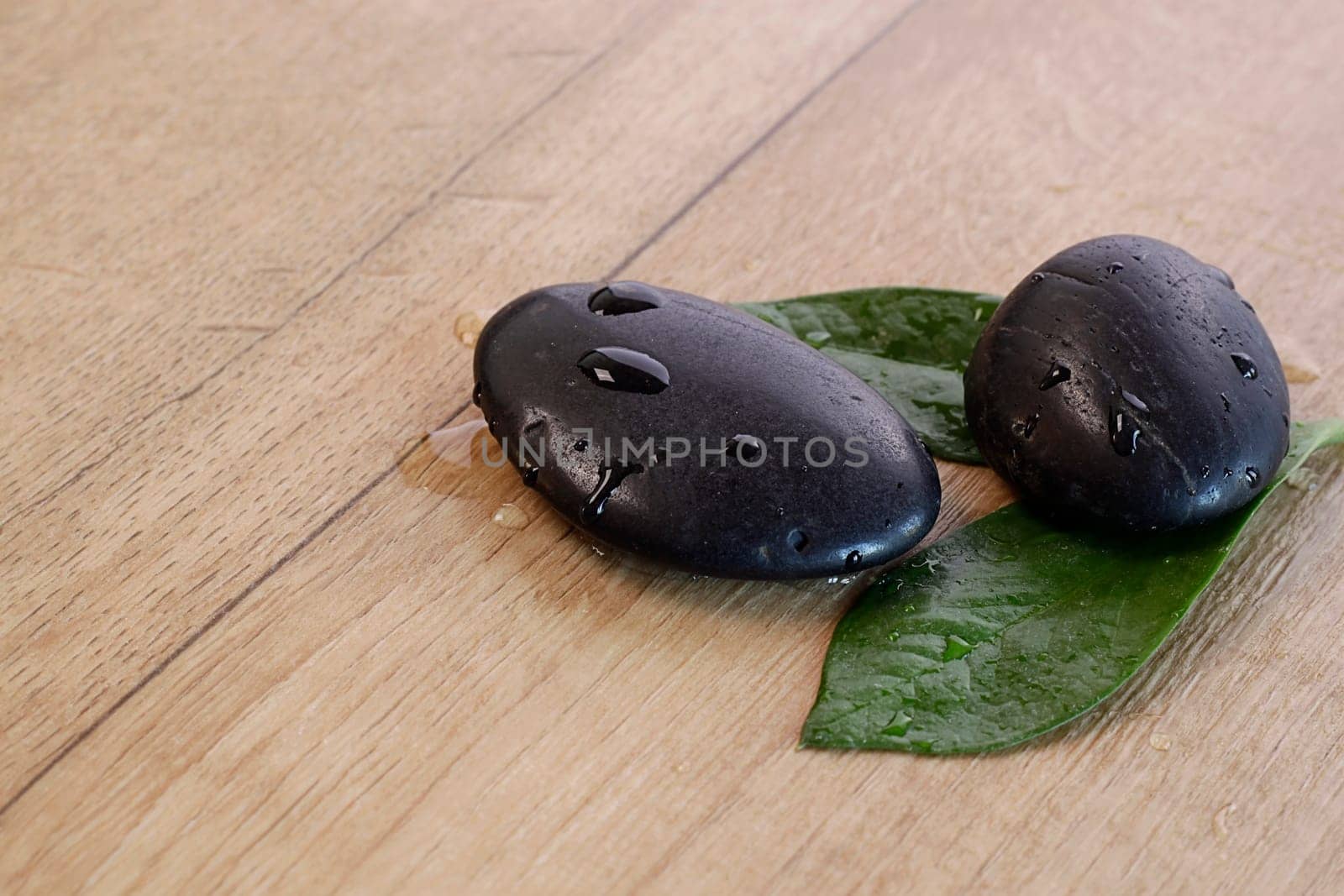 Hot Stones with green leafs on a wooden background