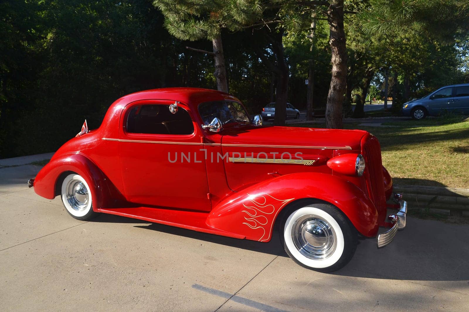 A beautiful red old car from around 1936, two door Buick with white tire, sitting in a driveway.