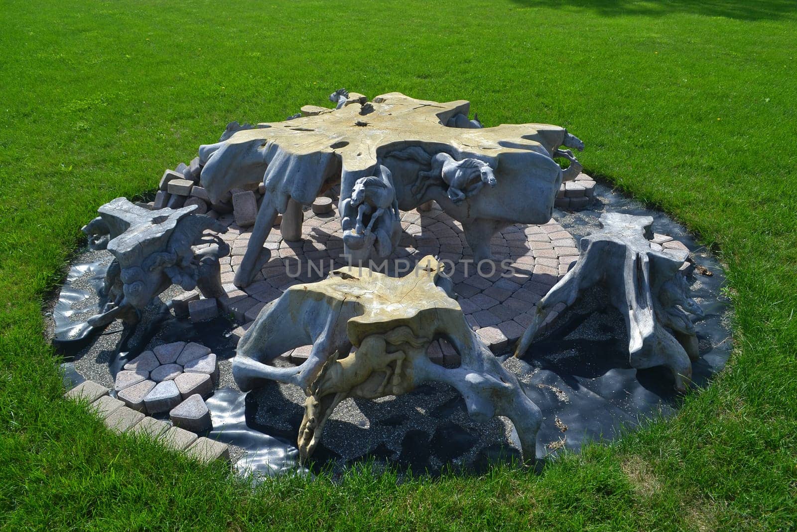 A beautiful set of four hand carved chairs and a hand carves table whit some horses on under construction in the back yard of a green lawn.