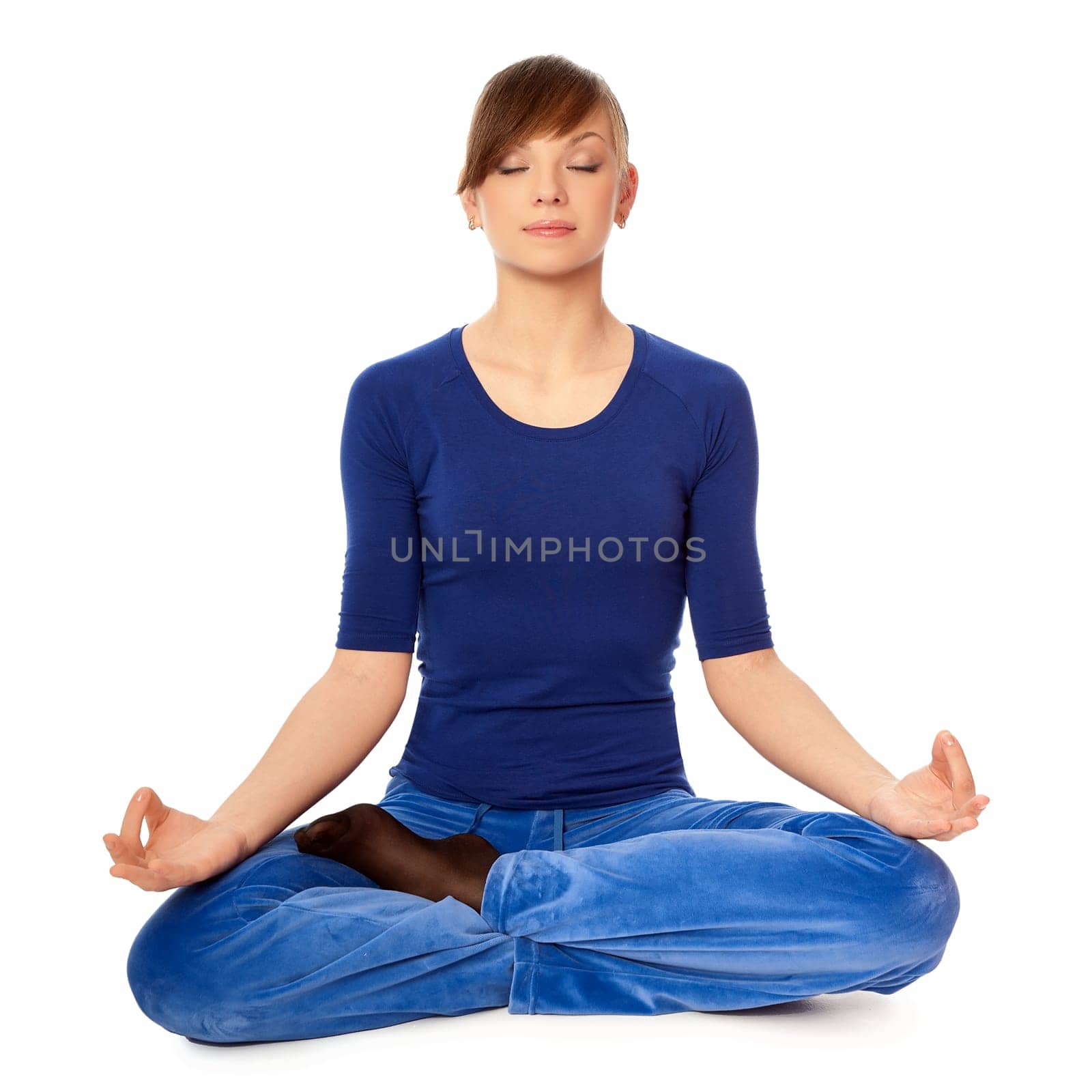 Woman sitting in lotus posture in the health club dressed in blue clothes and meditating