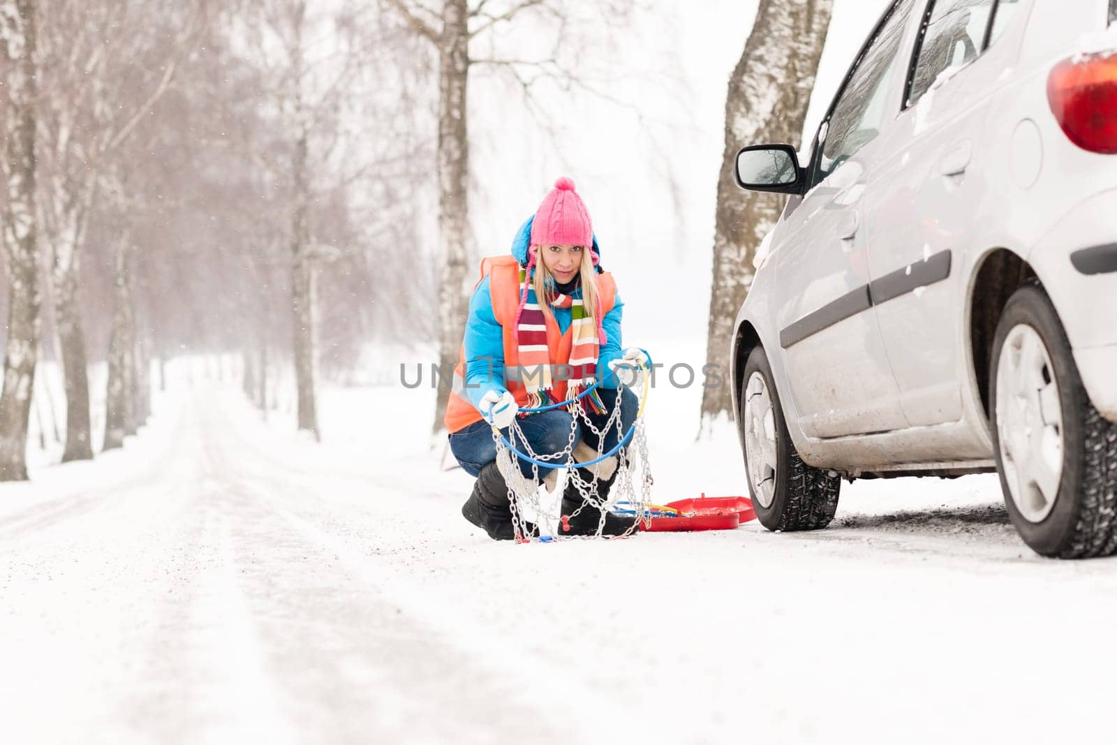 Woman with tire chains car snow breakdown smiling fixing winter