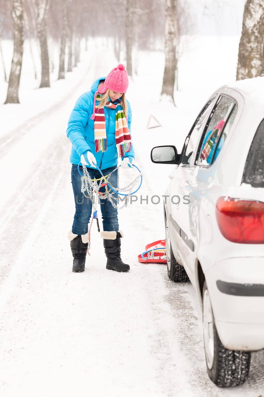 Woman snow standing with car tire chains holding winter broken