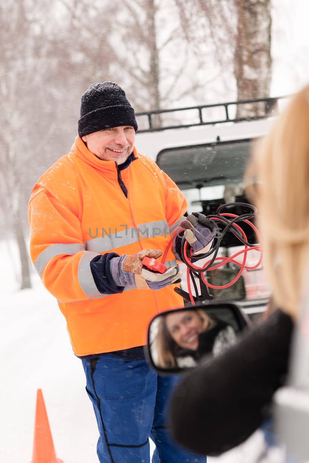 Man help woman broken car starting cables snow assistance winter
