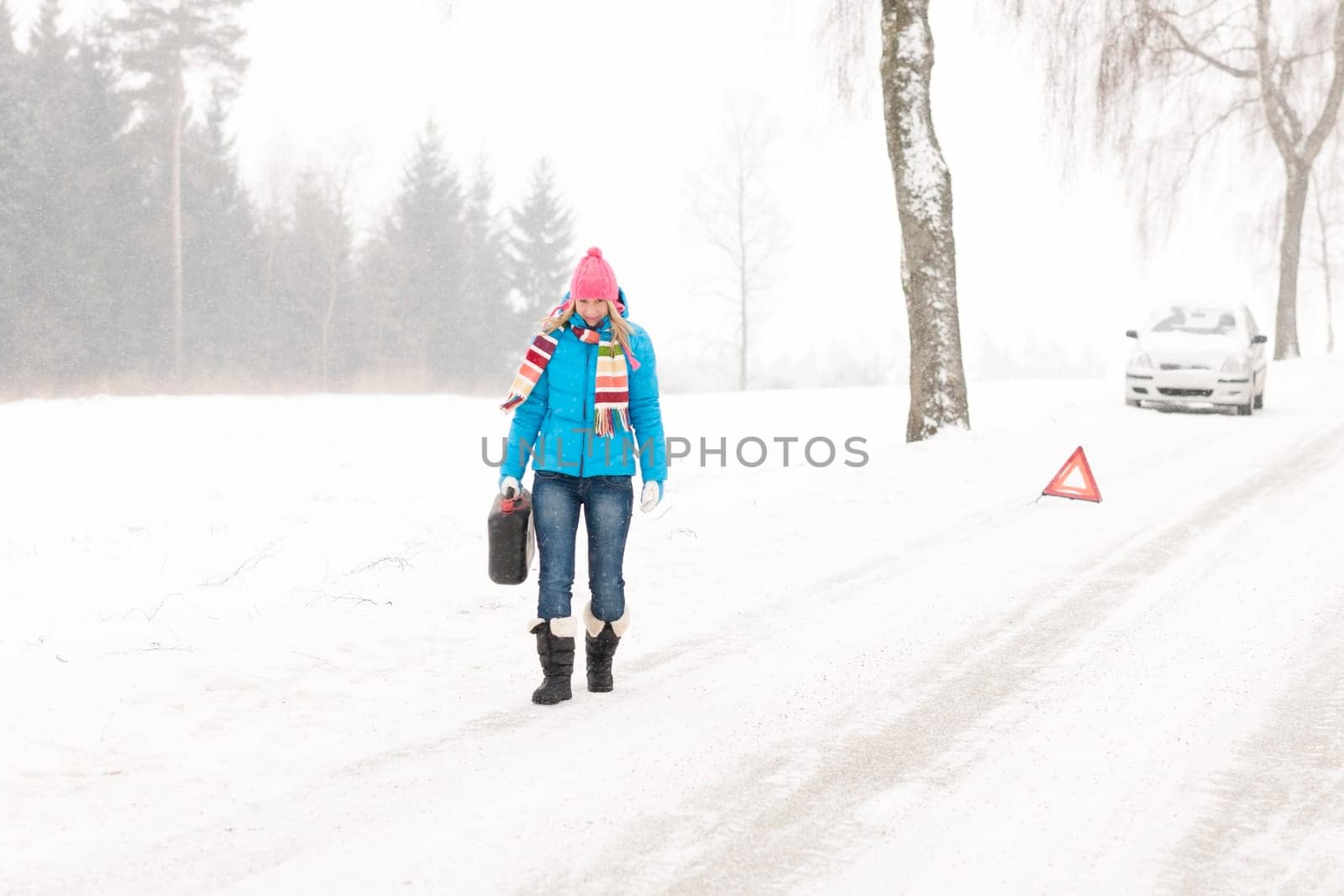 Woman carrying gas can snow car trouble winter breakdown walking