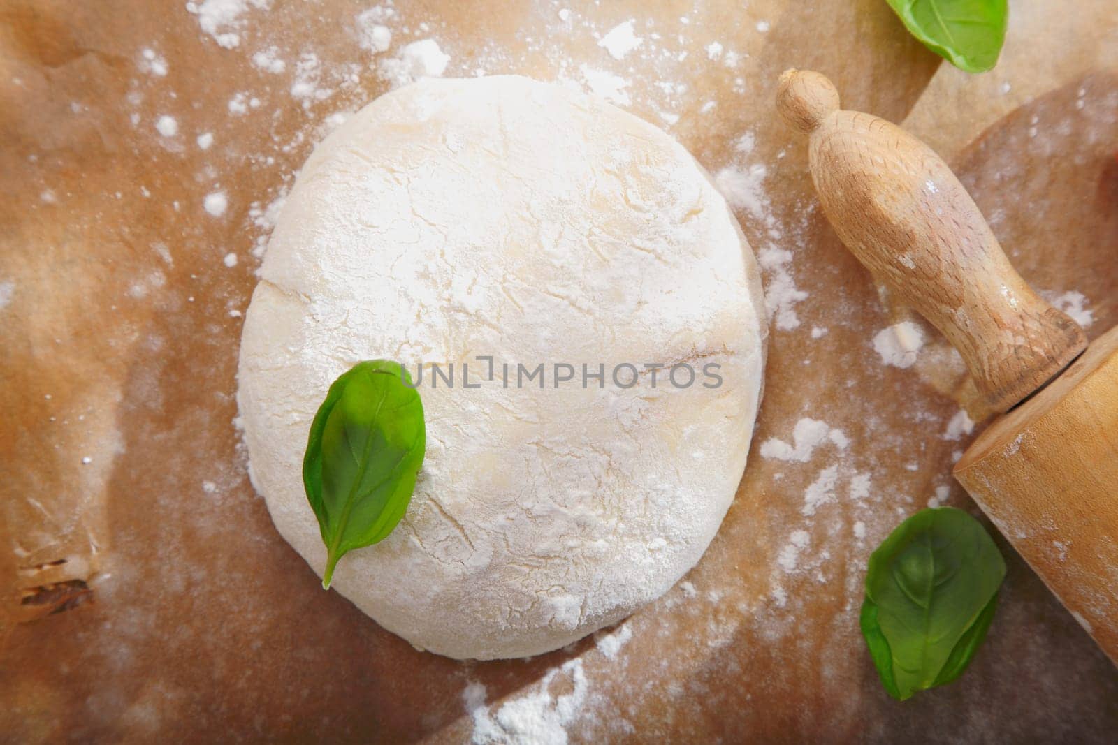 Fresh bread dough with a rolling pin on a wooden surface ready to be rolled out for a pizza base or pastry