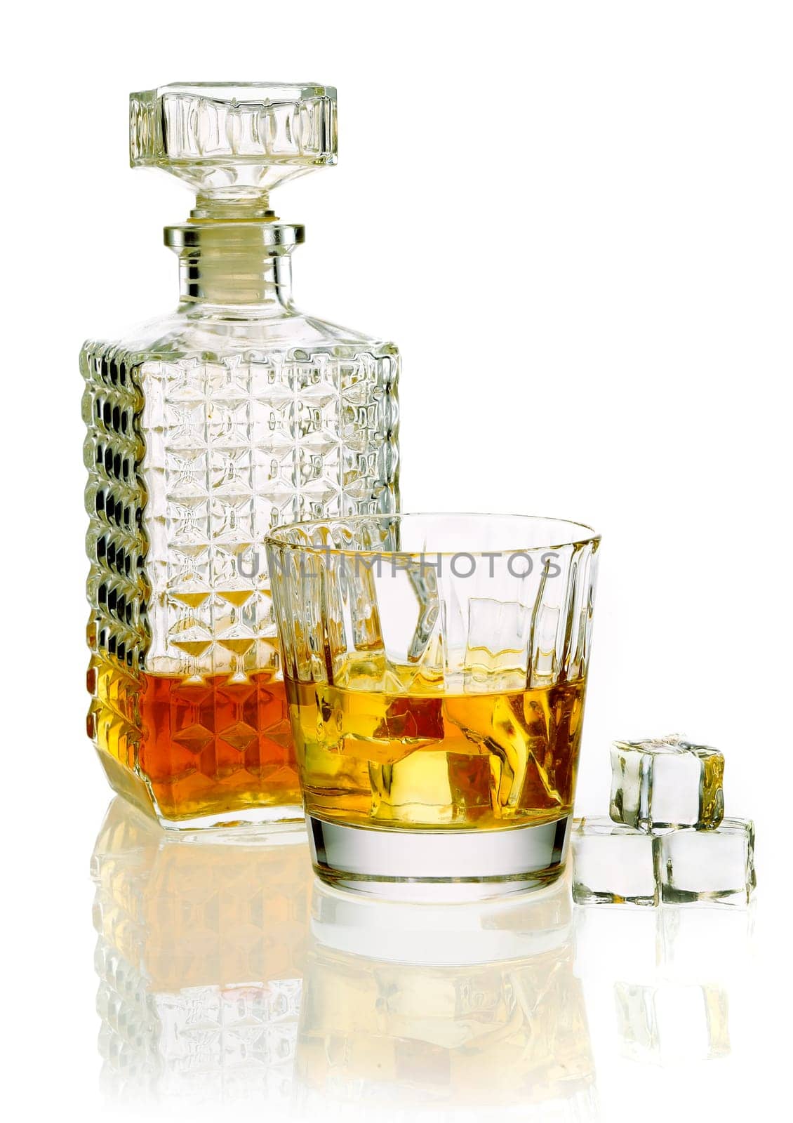 Whiskey or brandy decanter with a glass of whiskey on a reflective white surface
