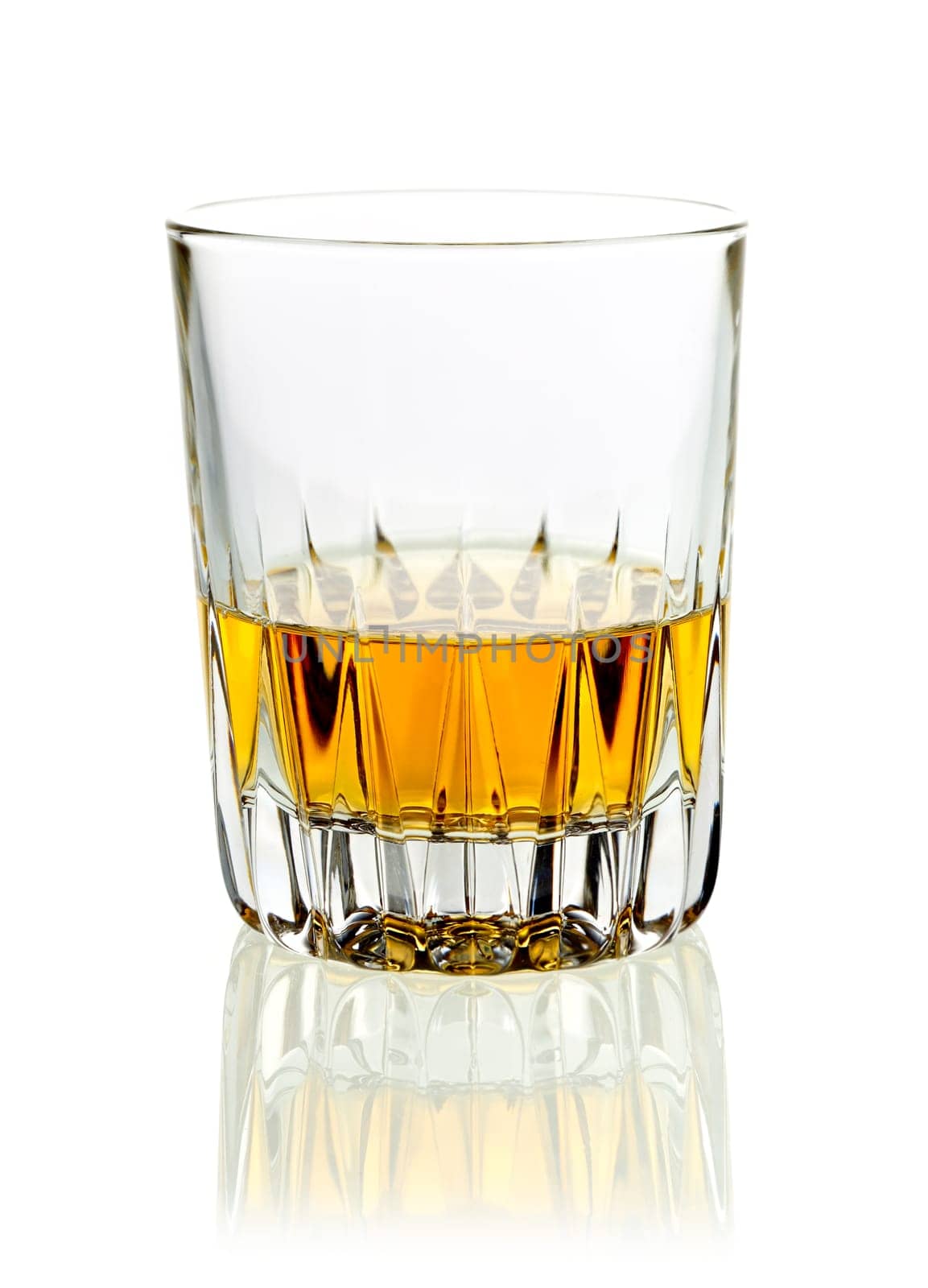 Tumbler of golden whisky or brandy served neat on a white studio background with reflection