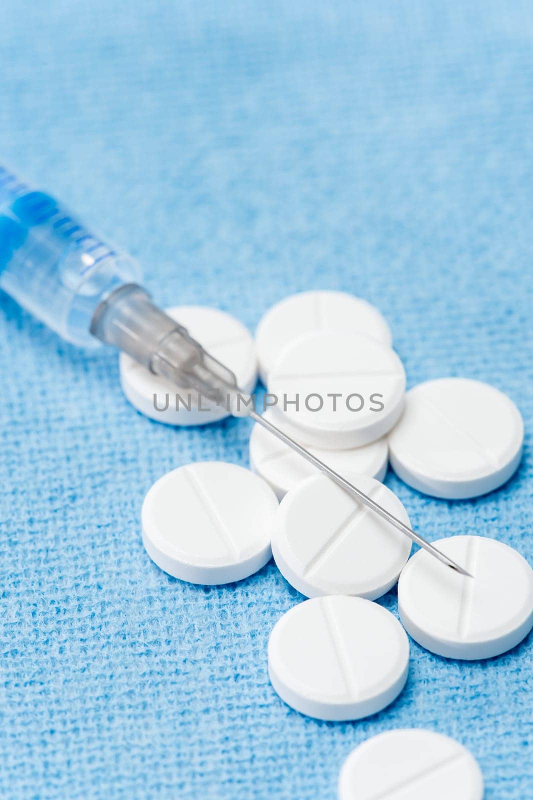 Injection needle with prescription pills blue background