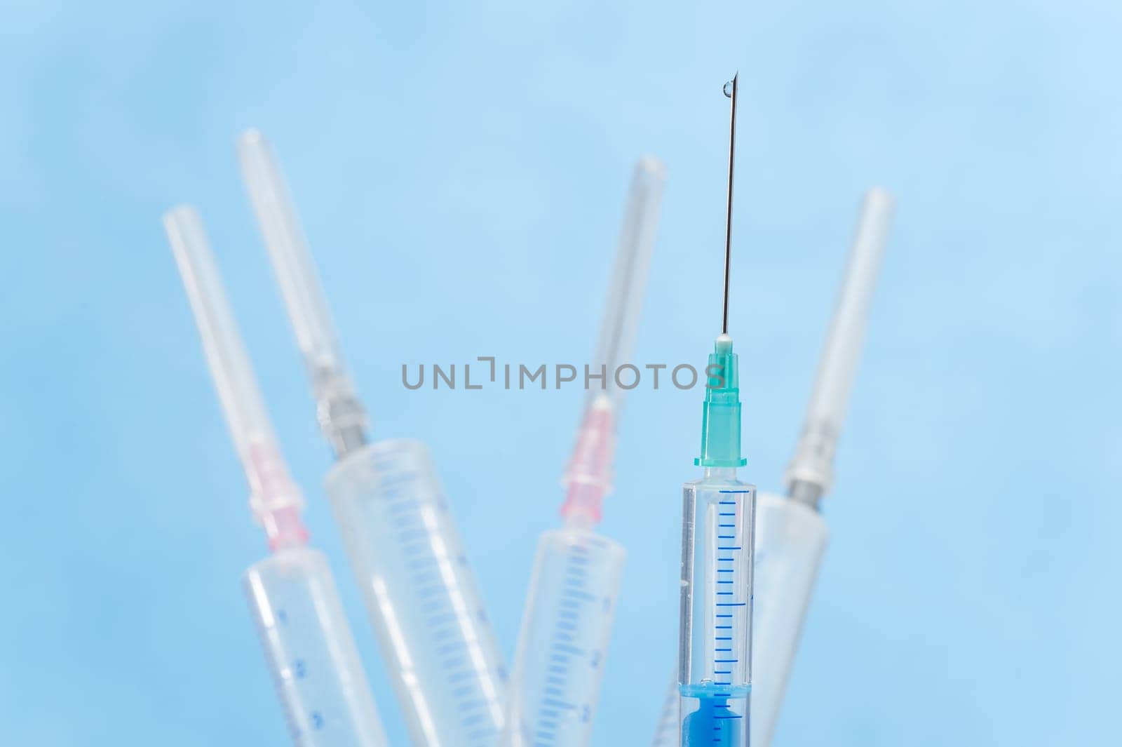 Transparent syringe with liquid drop falling from needle