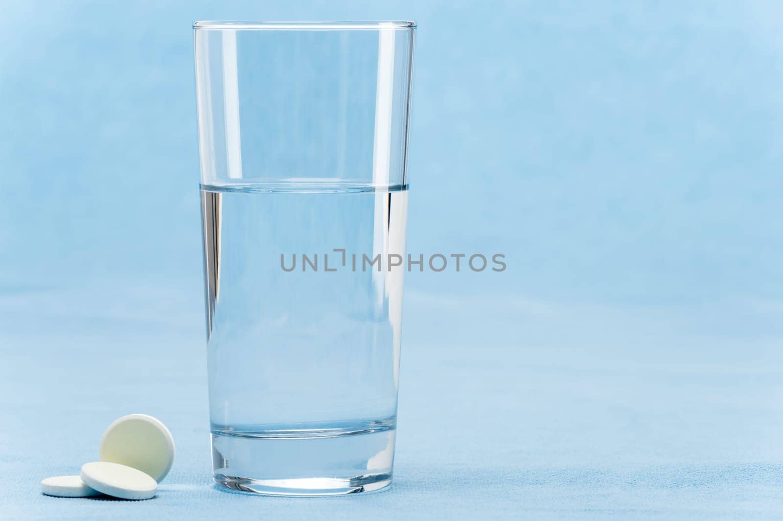 Soluble tablet throw in water glass on blue background