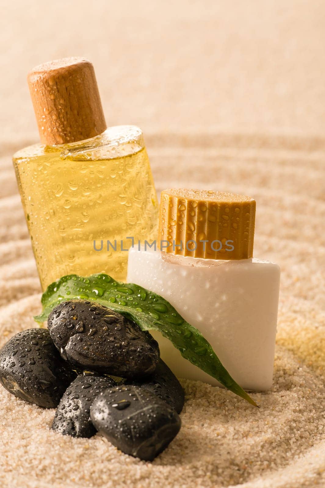 Spa therapy cosmetic products with zen stones on sand
