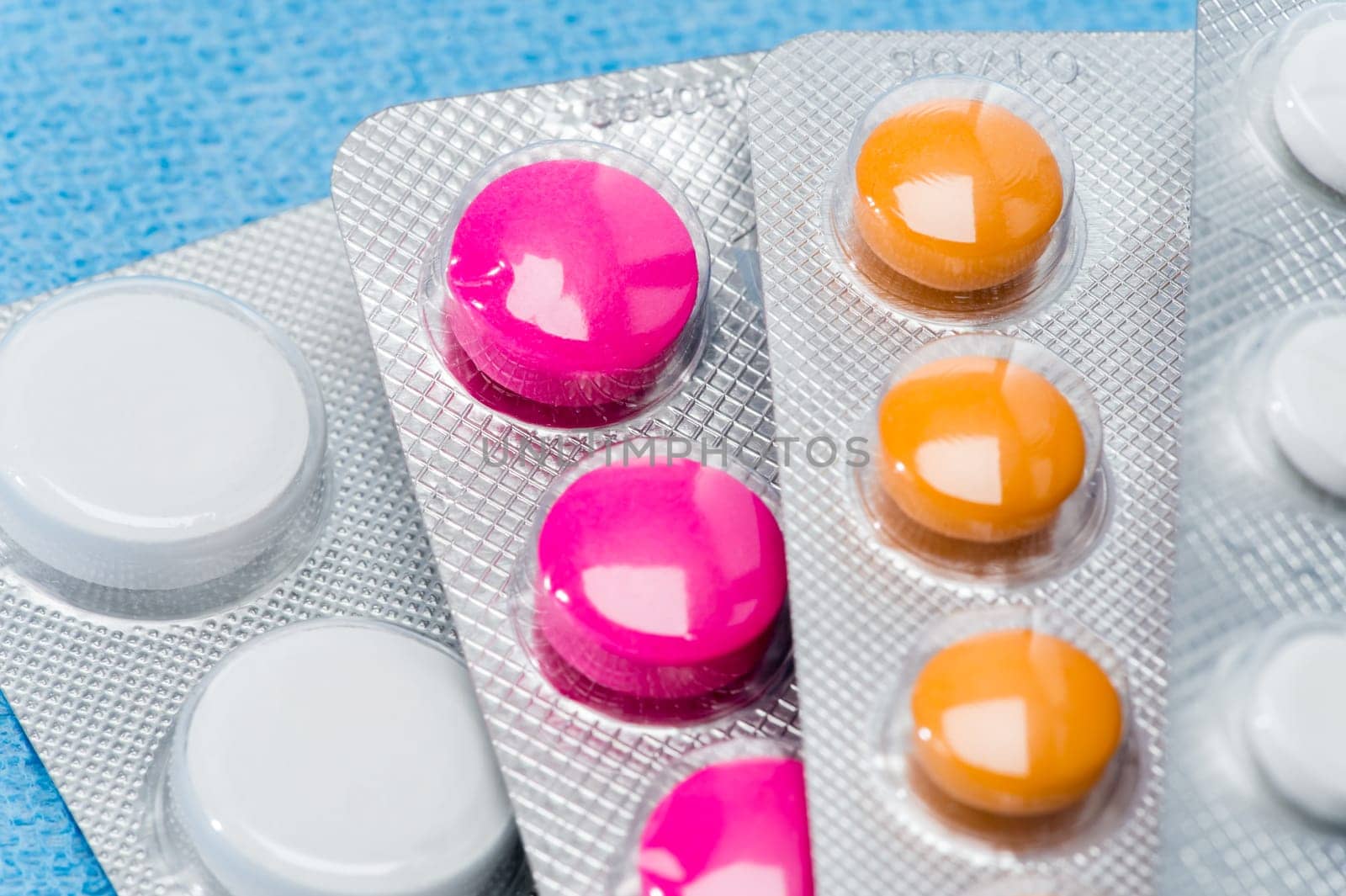 Blister packs of colorful medical pills tablets close-up on blue
