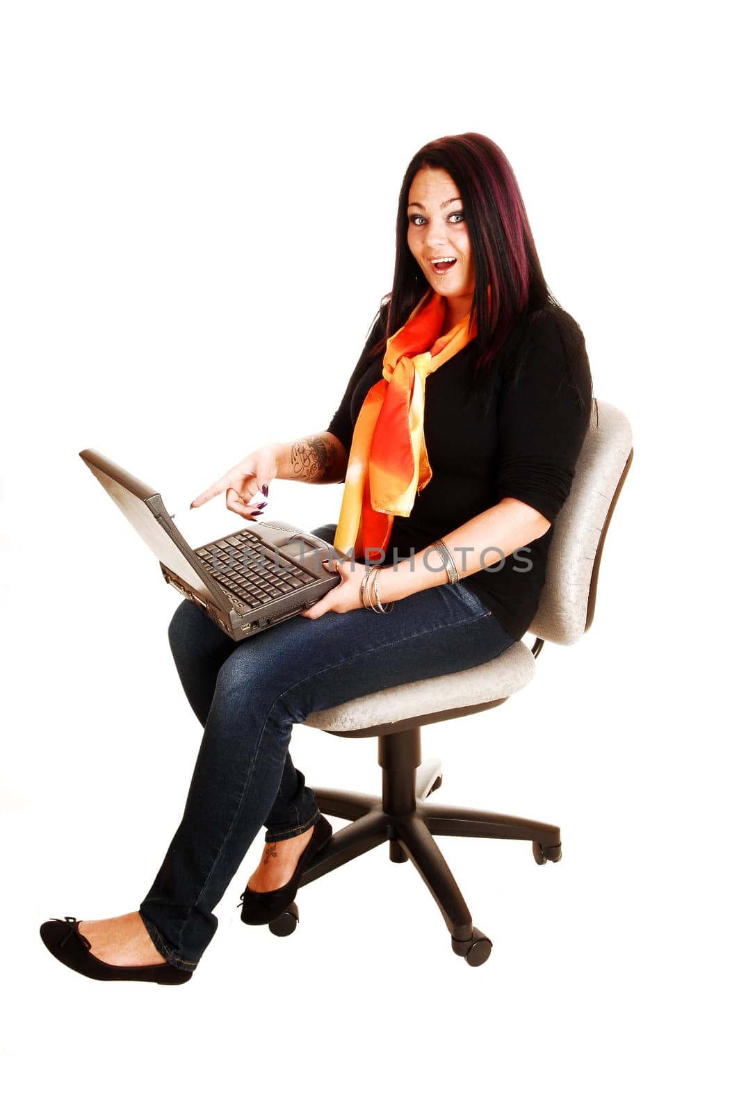 A young woman, sitting on an office chair with a laptop on her lap and found some very interesting staff, for white background.