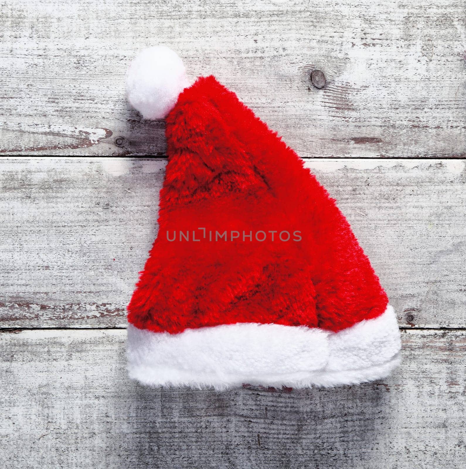 Red Santa Claus hat lying on rustic weathered wooden boards for a country Christmas greeting
