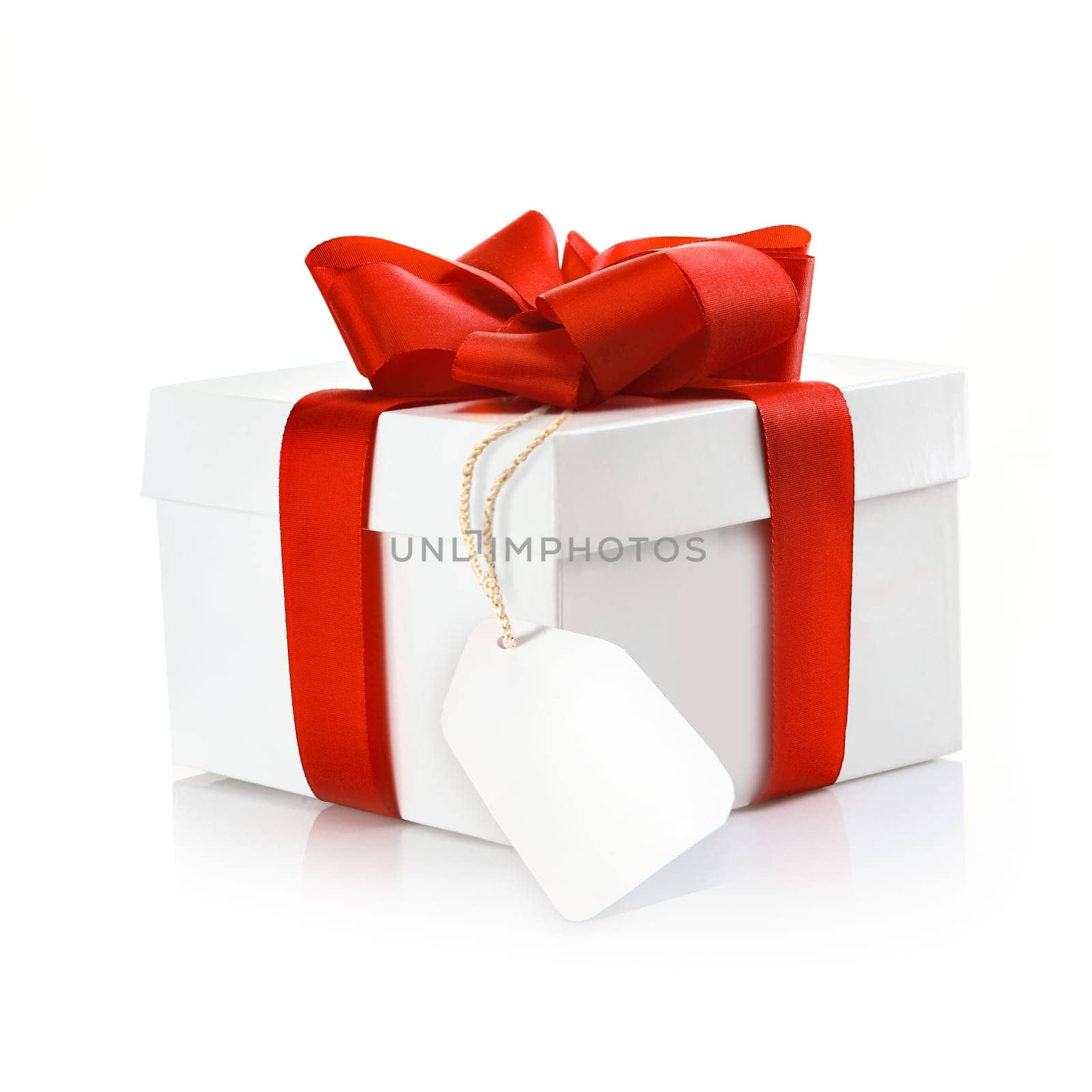 Christmas surprise gift with blank tag and a decorative red ribbon and bow on a white studio background