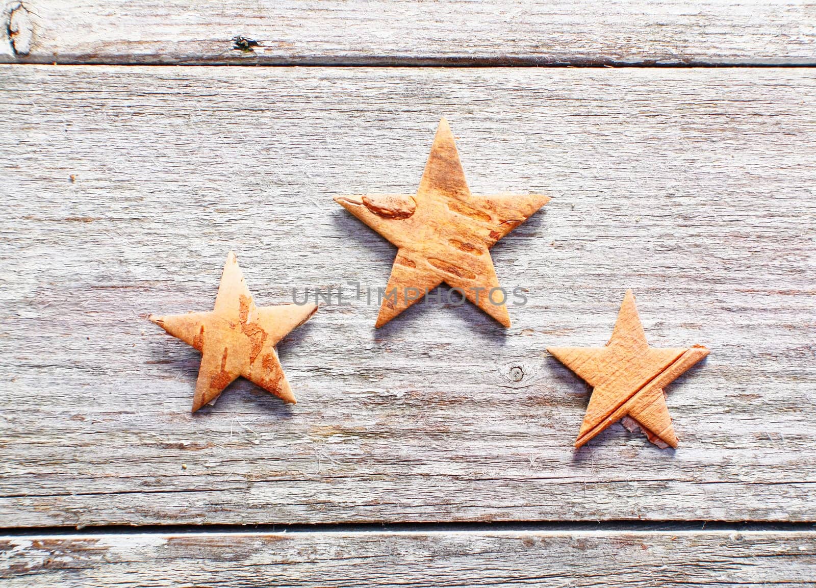 Three decorative Christmas stars on grungy weathered wooden boards with copyspace