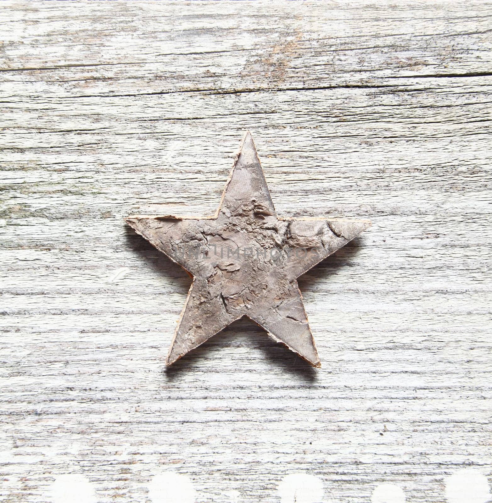 Grungy Christma background with a damaged peeling star centred on old textured cracked and weatherworn wood