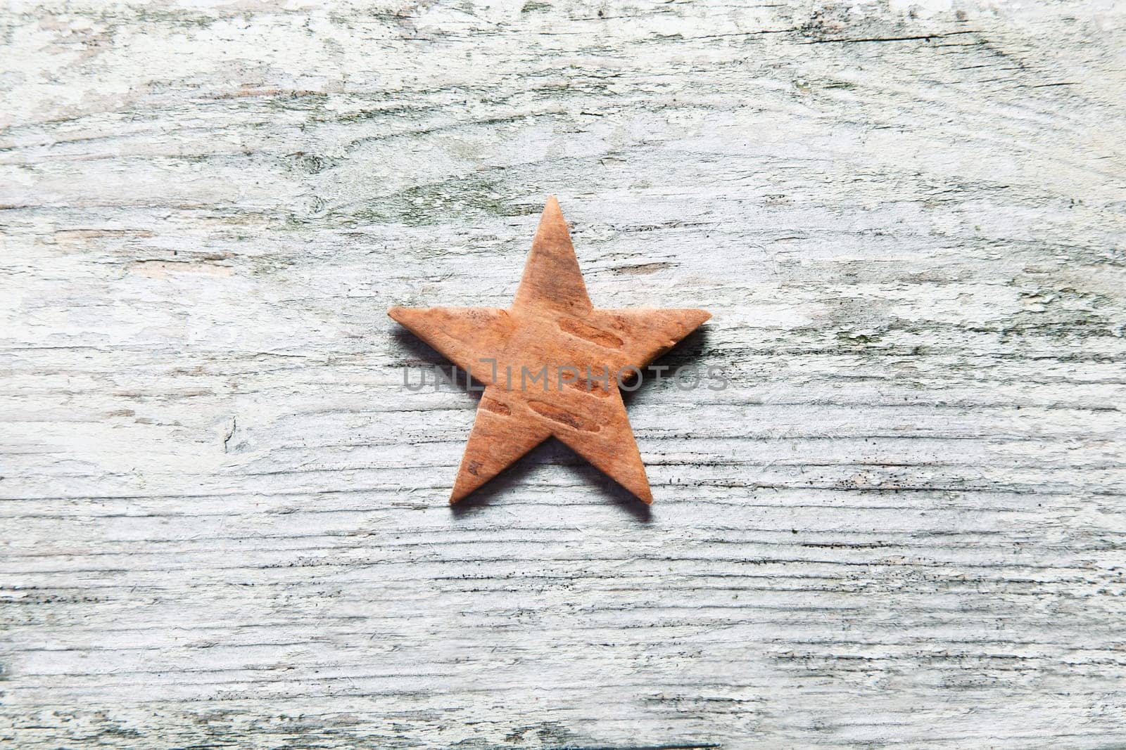 Rustic Christmas star centred on grungy old white weathered wooden boards with grain texture and copyspace