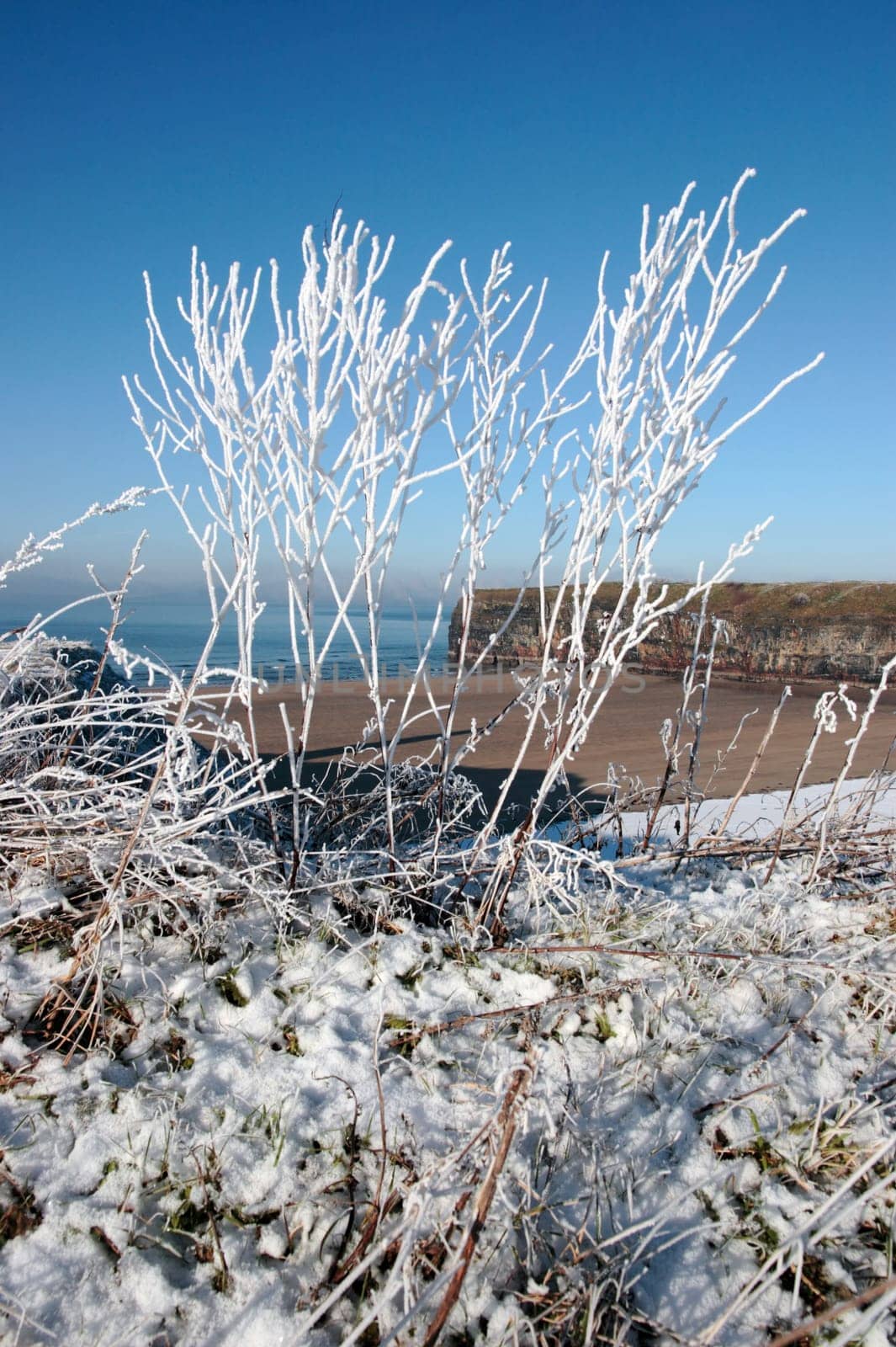 a seasonal snow covered view of atlantic ocean and ballybunion beach and cliffs on a frosty snow covered winters day