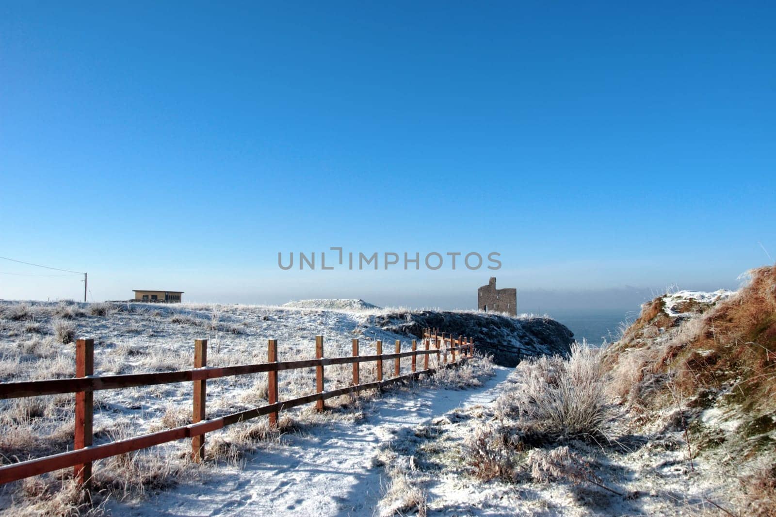 snow covered view of atlantic ocean and castle in ballybunion on a frosty snow covered winters day