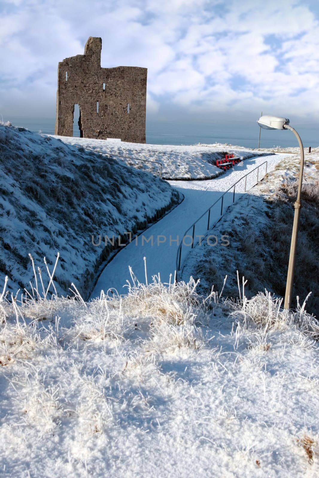 a seasonal snow covered view of atlantic ocean and ballybunion castle on a frosty snow covered winters day