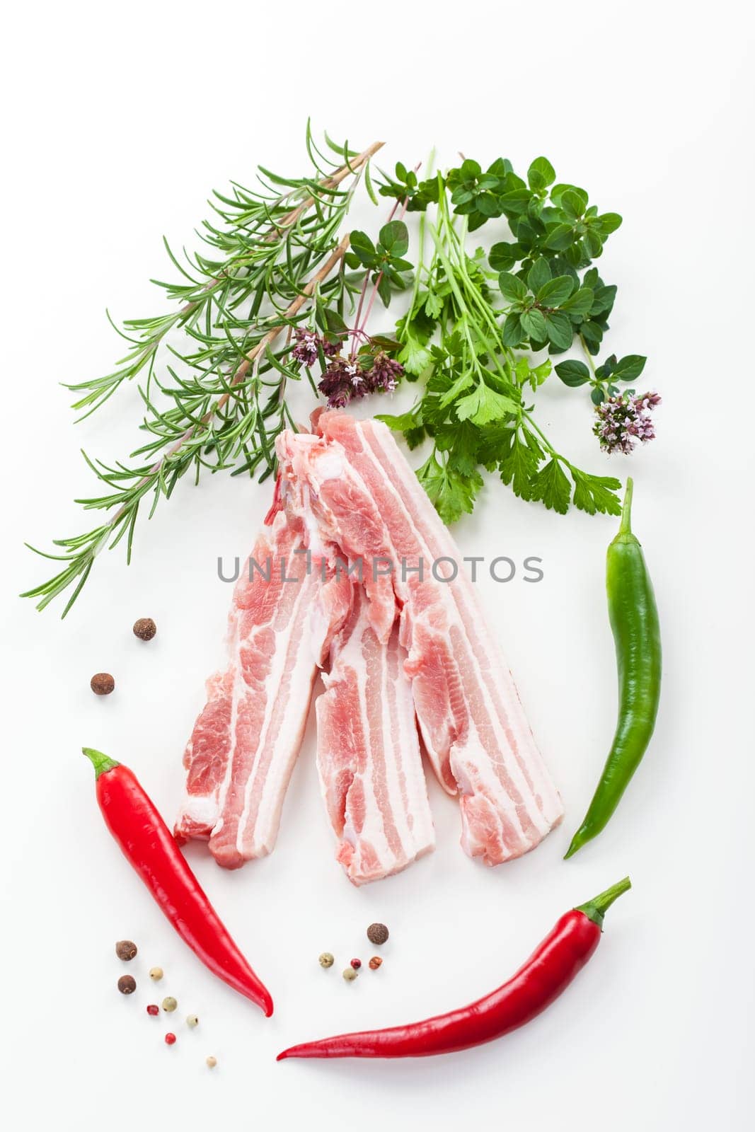 Raw spare ribs with rosemary on white background