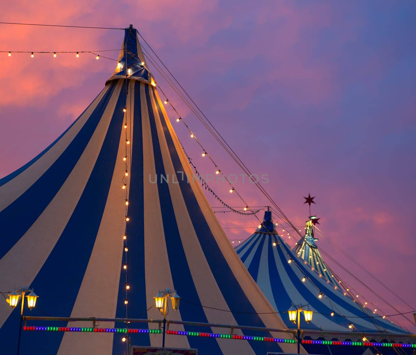 Circus tent in a dramatic sunset sky colorful orange blue with lights