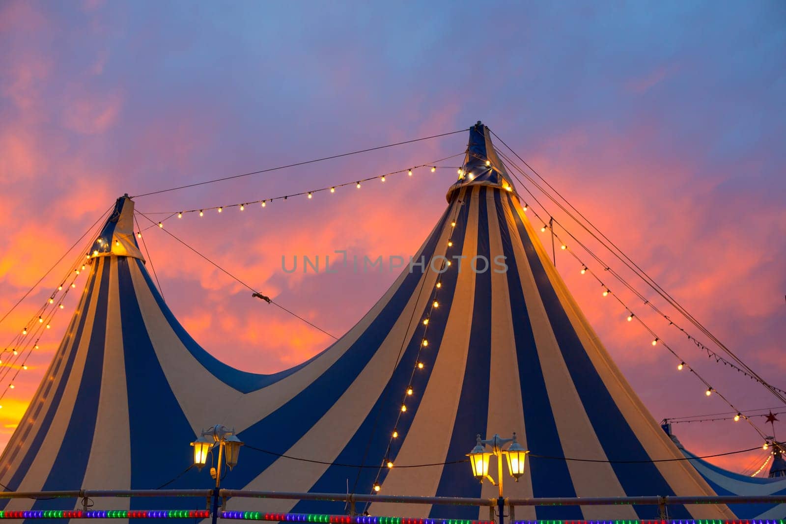 Circus tent in a dramatic sunset sky colorful orange blue with lights