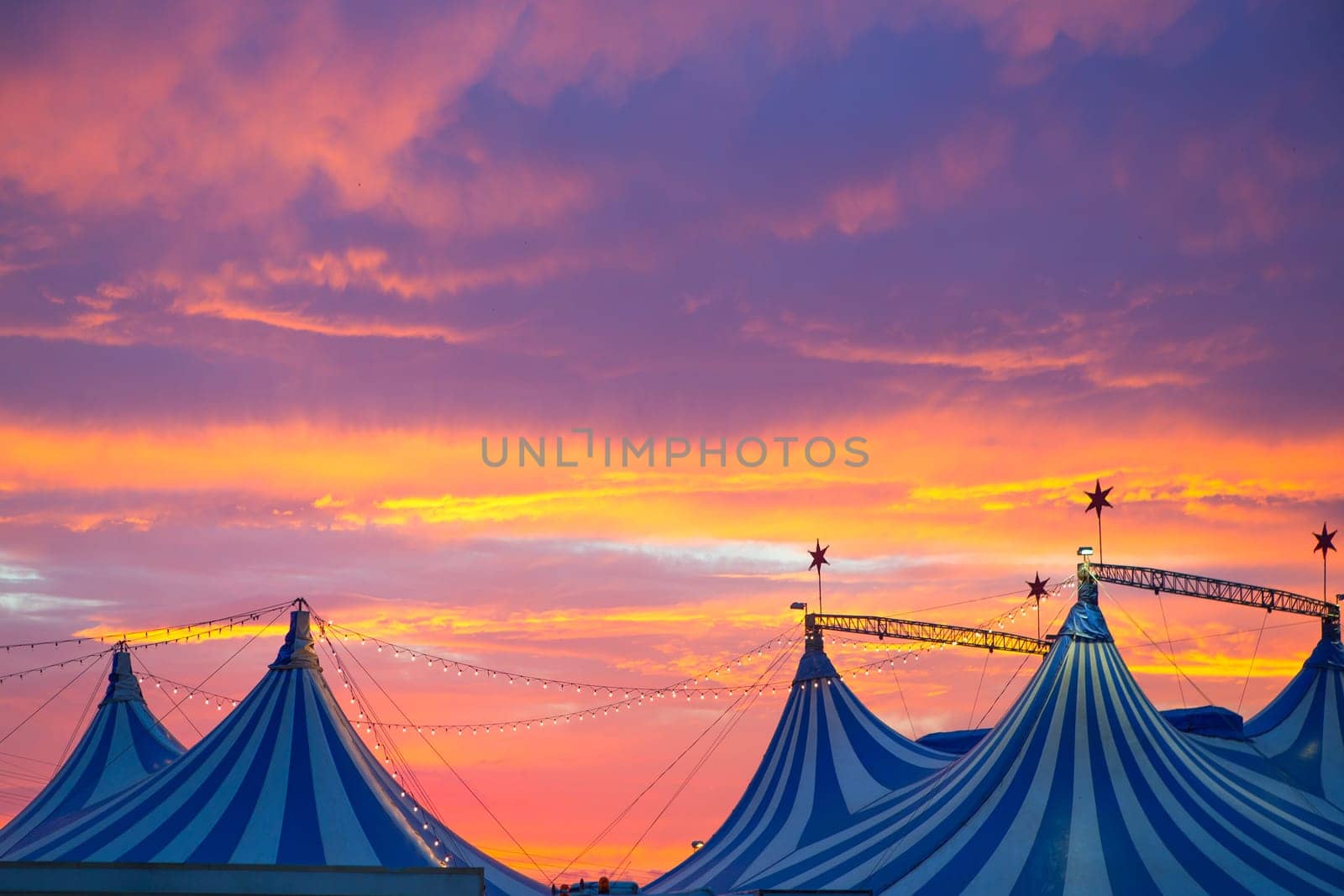 Circus tent in a dramatic sunset sky colorful orange blue with lights