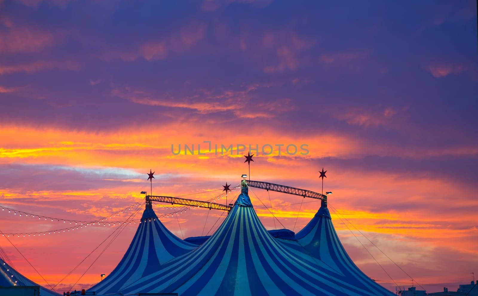 Circus tent in a dramatic sunset sky colorful orange blue with lights