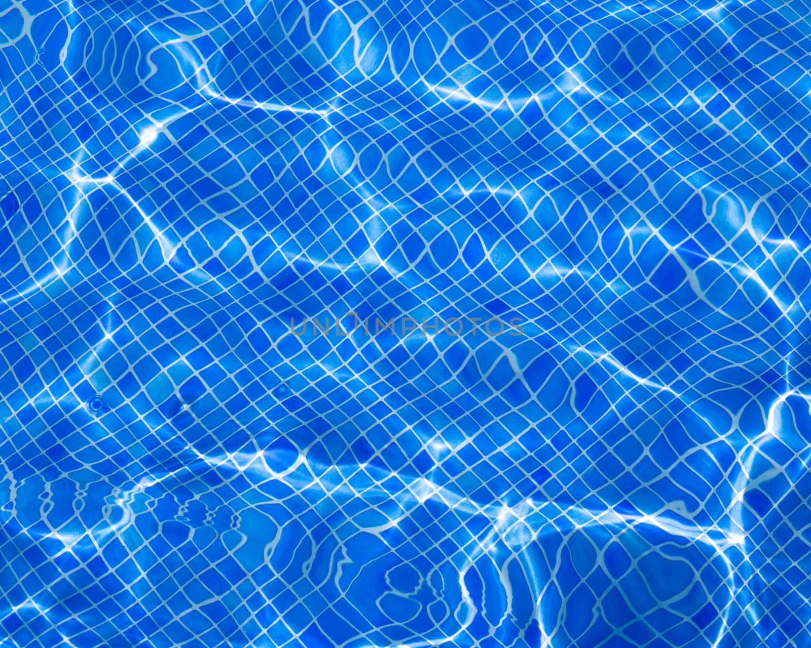 Blue tiles pool with ripple water reflection as a summer background