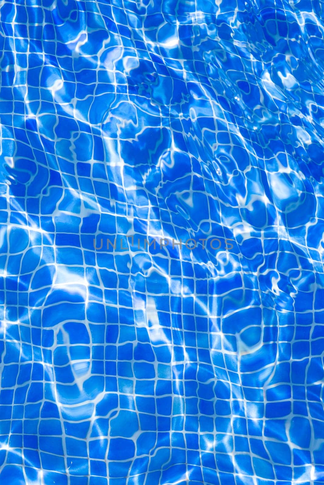 Blue tiles pool with ripple water reflection as a summer background