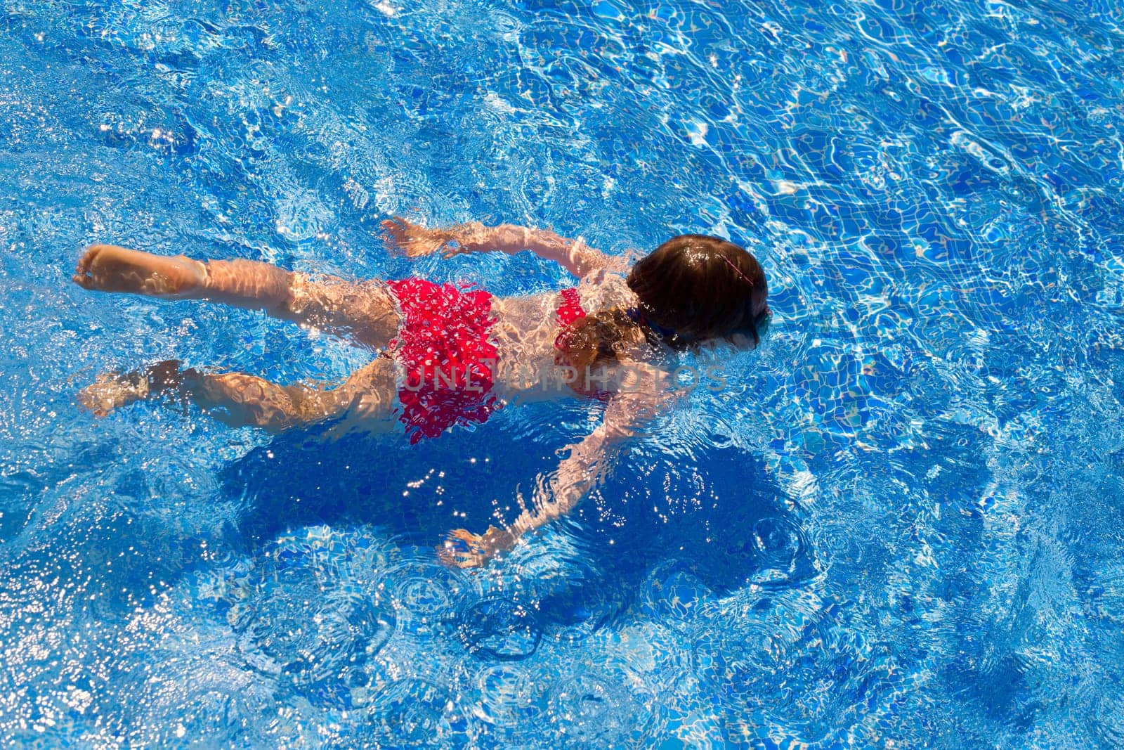 bikini kid girl swimming on blue tiles pool in summer vacation