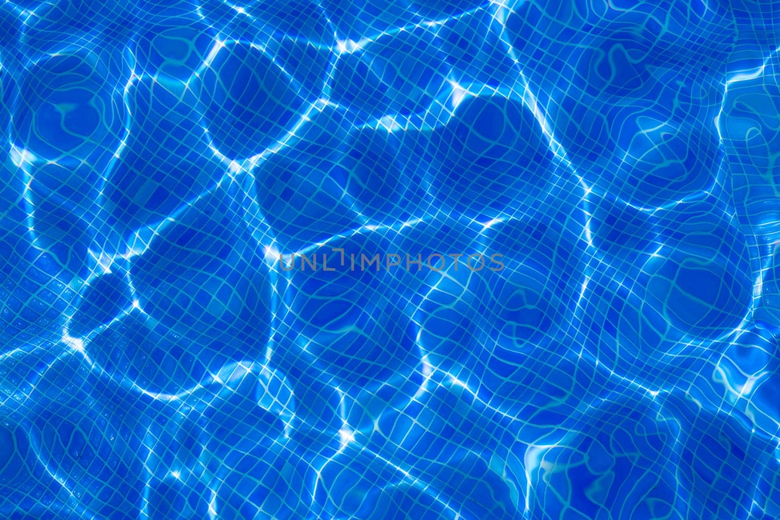 Blue tiles pool with ripple water reflection as a summer background