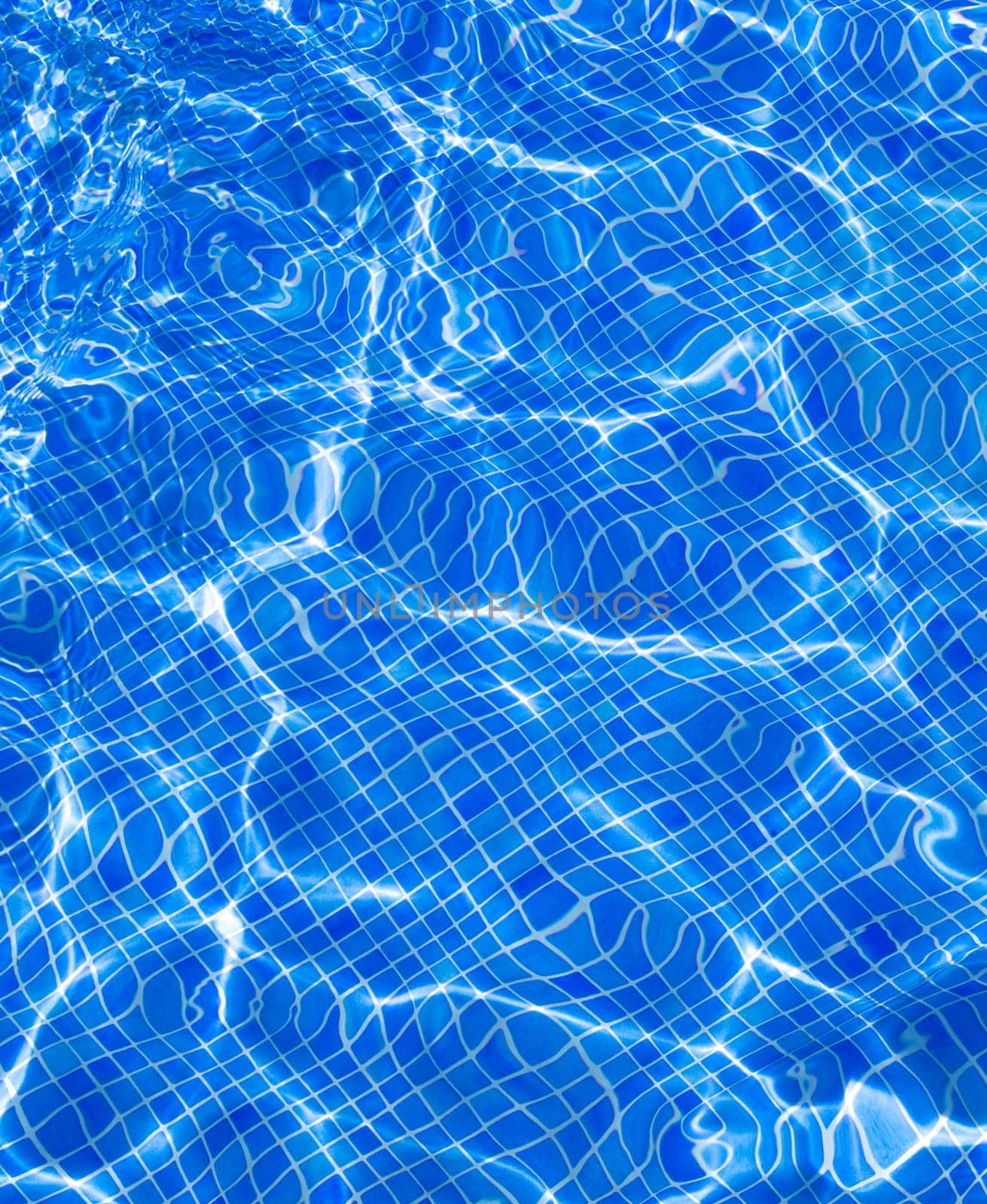 Blue tiles pool with ripple water reflection as a summer background