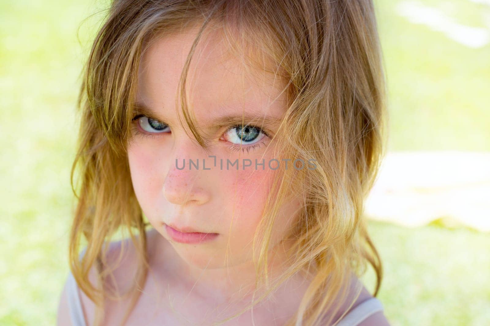 Angry blond children girl portrait looking at camera