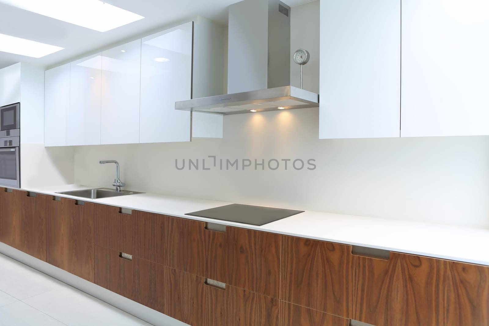 Actual modern kitchen in white and walnut wood interior house