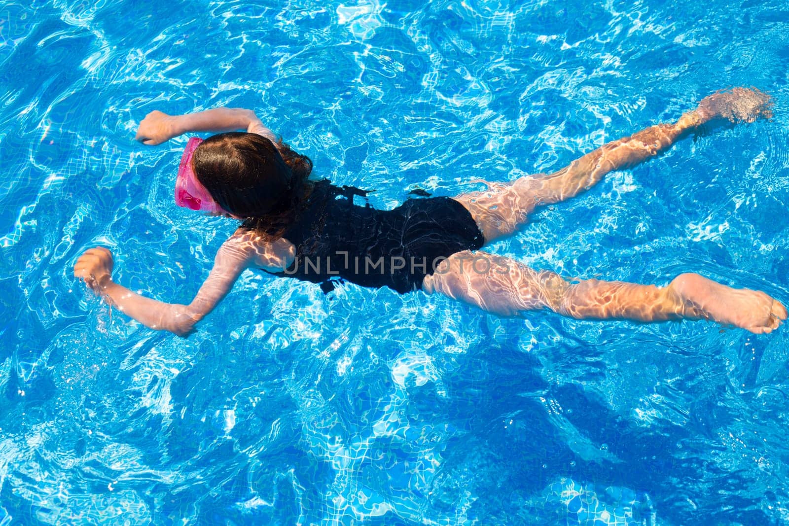 bikini kid girl swimming on blue tiles pool in summer vacation