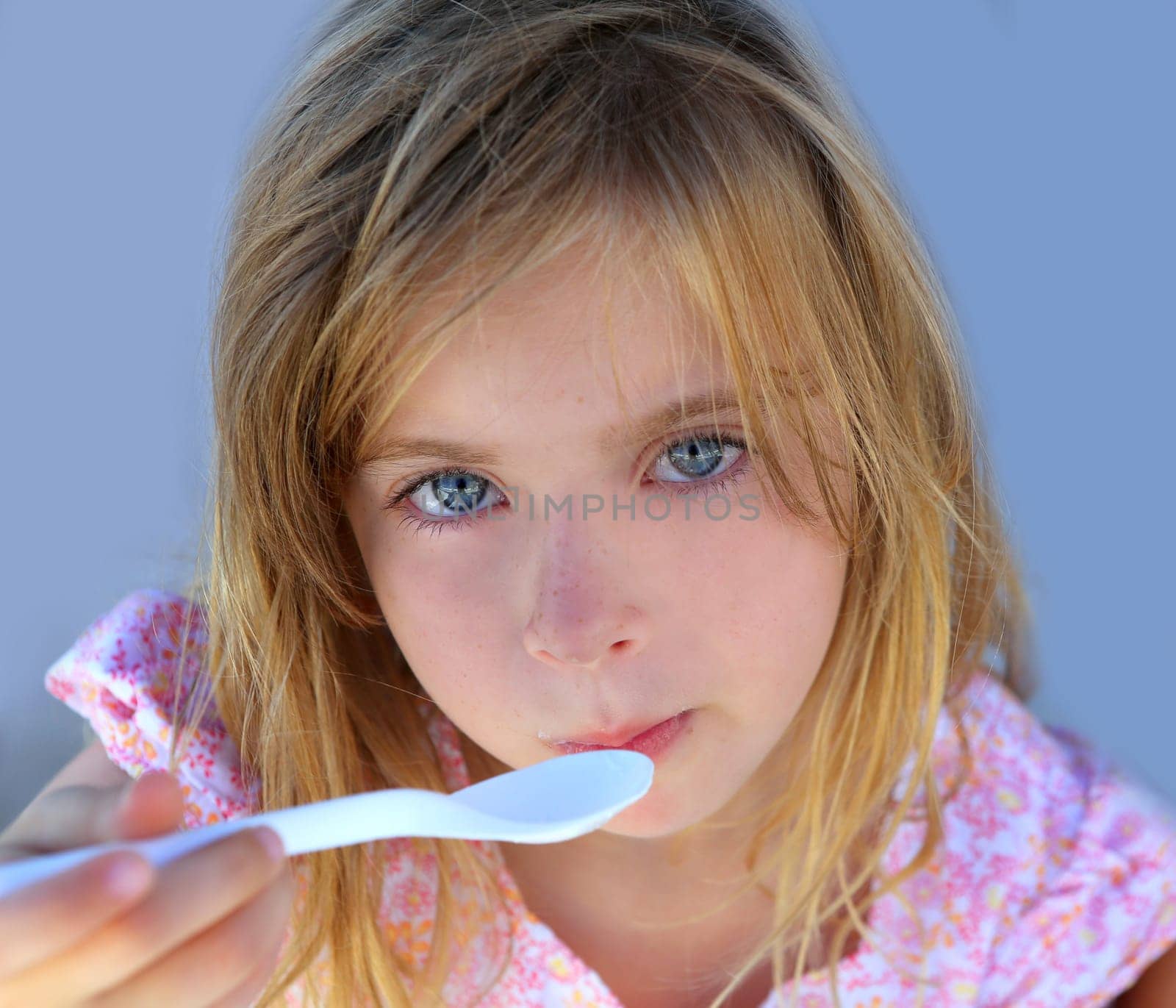 Blue eyes kid girl eating breakfast with spoon portrait