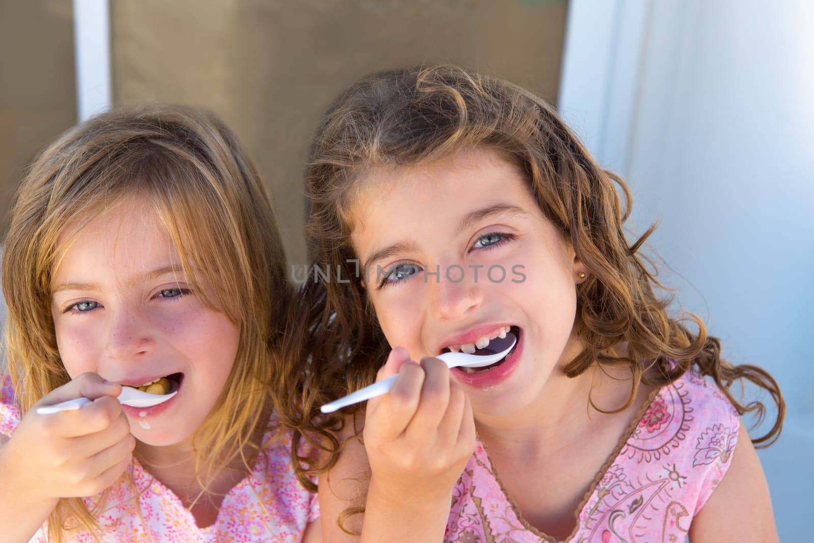 Blue eyes kids sister girl eating breakfast with spoon