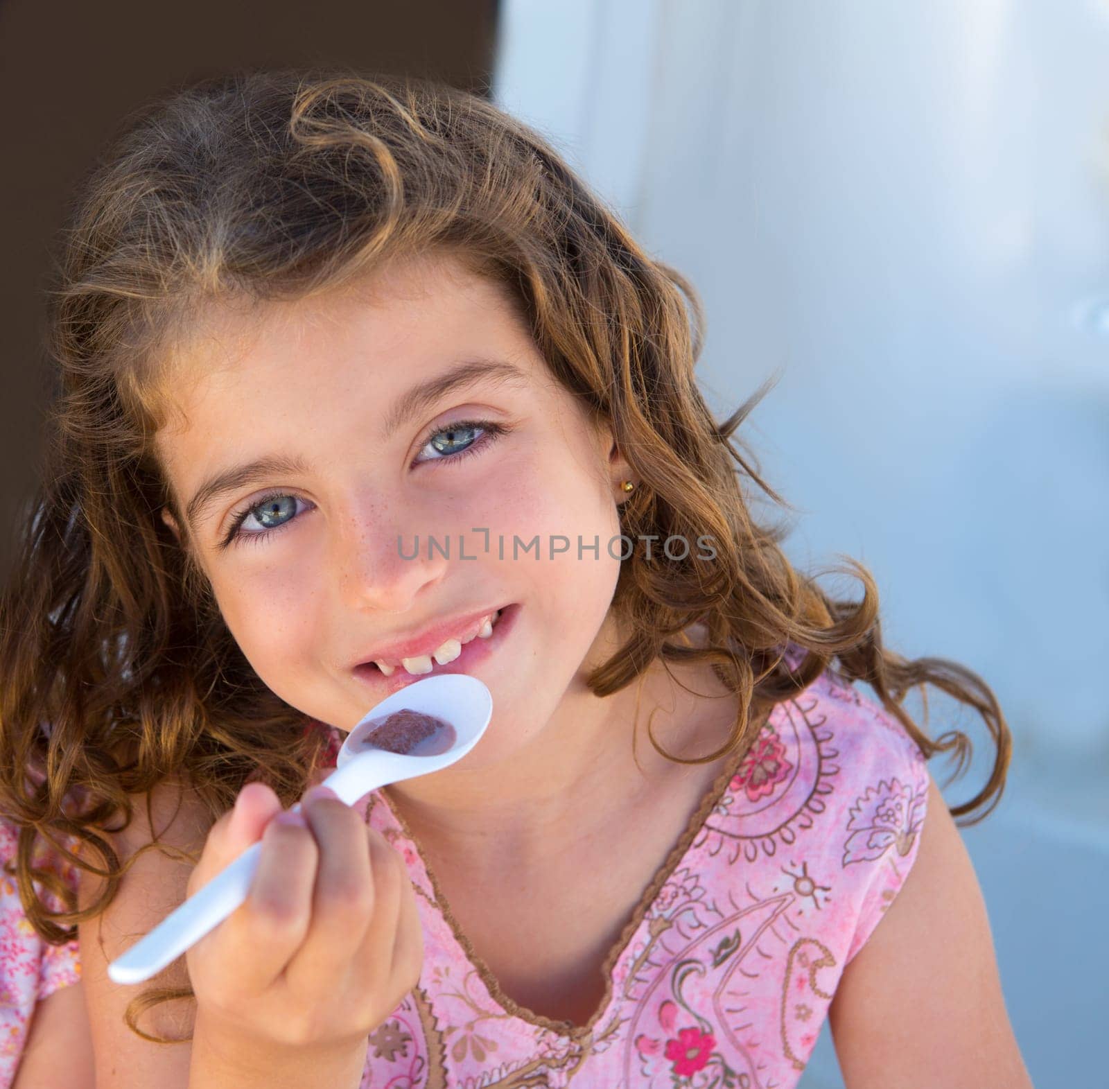 Blue eyes kid girl eating breakfast with spoon portrait