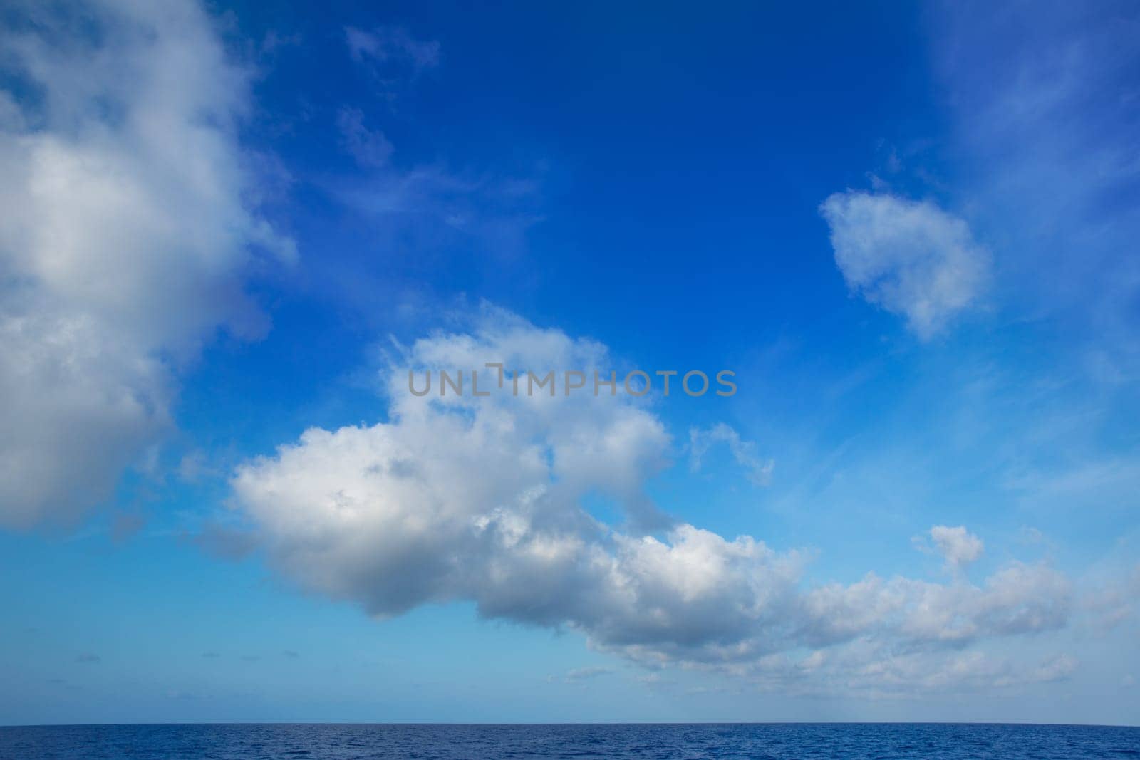 cumulus clouds in blue sky over ocean water horizon